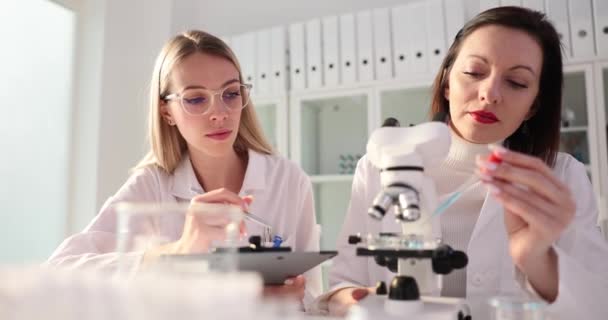 戴眼镜的妇女在临床教授和帮助化学专业的年轻学生进行研究 员工在实验室里发现新的科学液体 — 图库视频影像