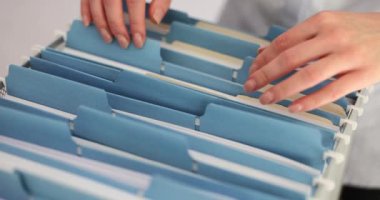 Yönetici, iş belgelerinin bulunduğu klasörleri arıyor ve alıyor. Arşiv kutusunda muhasebe belgeleri arayan kadın muhasebeci.