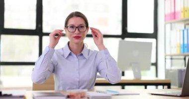 Dost canlısı ofis çalışanı yönetici gözlüklerini çıkarır ve kameraya güvenle bakar. İş yerinde başarılı ofis yöneticisi veya yönetici