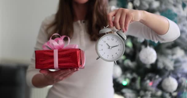 目覚まし時計と新年の贈り物を持った女性 クリスマスと新年のギフトを計画して選択する時間 — ストック動画