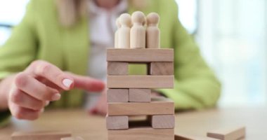 İş kadını lideri ve girişimci, insanların figürünün üzerindeki riskli yapıdan tahta blokları kaldırıyor. Hayat ve iş sigortası