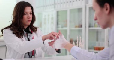 Ortopedik doktor hasta bileğine beyaz elastik bandaj uygular. Spor sakatlığı nedeniyle bilek ağrısı.