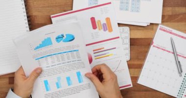 Finansal belgelerle çalışan ve iş mali verilerini analiz eden bir işadamı. Pazarlama verileri ve istatistikleri