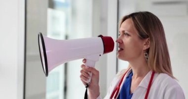 Genç bayan doktor megafona bağırıyor ve tıbbi teklifini bildiriyor. Tıp merkezinde promosyonlar ve indirimler
