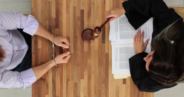 コンヴィクトは手錠をかけられ 裁判官は木製のテーブルの上のビューで文を発音する オファーと正義 — ストック動画