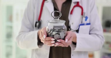 Doktor şeffaf domuz kumbarasını bozuk paralarla tutuyor. Sağlık giderleri ve tasarruf masrafları