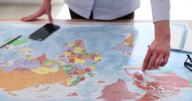 Sıradaki maceraperest kadın elini planlamak oyuncak uçağı dünya haritasına taşıyor. Turist dünya haritası ve masadaki uçuşları öğreniyor