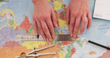 Dişi eller dünya haritasındaki mesafeleri cetvel ve pusula kullanarak ölçer. Turist dünya haritasındaki mesafeleri ölçmek için cetvel kullanıyor