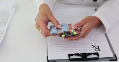 Kadın doktor elinde çeşitli hap kabarcıkları olan bir paket tutuyor. Hastalığın tedavisi ve tedavisi