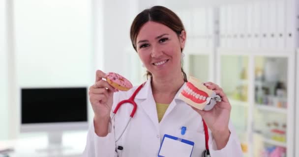 Plastikkiefer Und Ein Süßer Rosafarbener Donut Der Hand Eines Zahnarztes — Stockvideo