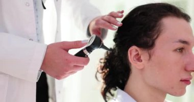 Erkek hasta kulağı otoskop kullanılarak inceleniyor. Otitis semptomlara ve tedaviye neden olur.