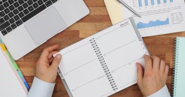 İş adamının elleri planlama günlüğünün sayfalarını çevirir. Günlük 2024 ve gelecek planları