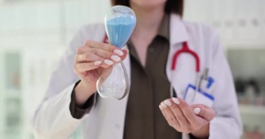 Kadın doktor klinikte kum saati tutuyor. Doktor için zaman yönetimi
