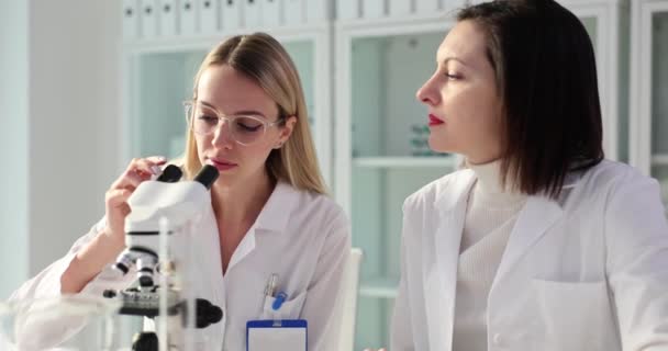 Een Team Van Wetenschappers Kijkt Door Microscoop Deelt Samen Informatie — Stockvideo
