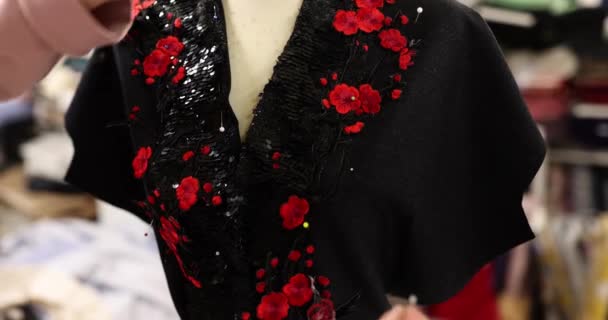アトリエで女性のスーツやドレスを縫います ファッションデザイナーはマネキンのドレスの襟に花を付けるためにピンを使用します — ストック動画