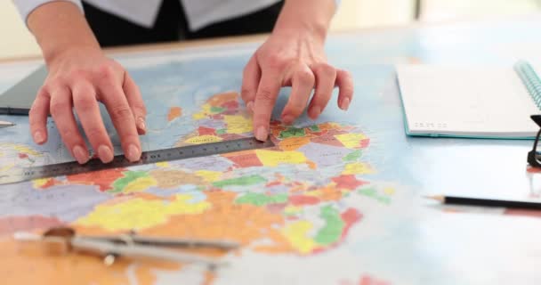 女性はテーブルのルーラーで地図上のポイント間の距離を測定します 女性旅行代理店は 正確な計算を提供する地図上の測定ツールを配置します — ストック動画