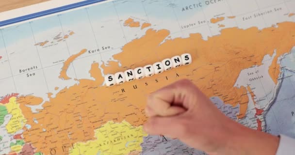 ロシアの地図上の言葉制裁と オフィスで拳を打つ男 隣国の土地に侵入するためのテロリスト国を罰する ストップ — ストック動画