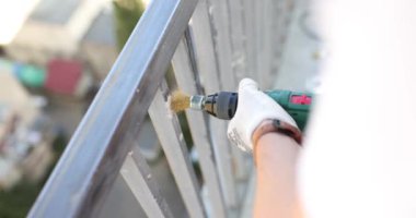 Pamuk eldivenli işçi evde elektrikli aletle balkon metal çerçevesini parlatıyor. İşçi, terasta çit kirişini işliyor. Ev onarımı