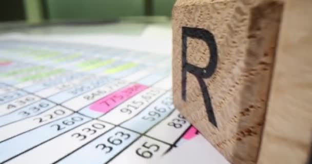 办公室桌子上的木制立方体中的小字收入记录在公司最新的收入文件上 会计提交的业务年度报告 — 图库视频影像