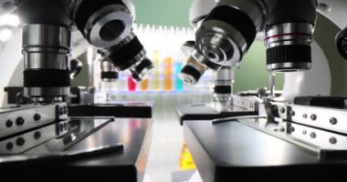 Elektronik mikroskoplar laboratuvar masalarına yerleştirilmiş. Laboratuvar asistanları kimyasalları güçlü mikroskoplar altında inceler. Laboratuar, asistanlar için öğrenme ortamını teşvik ediyor