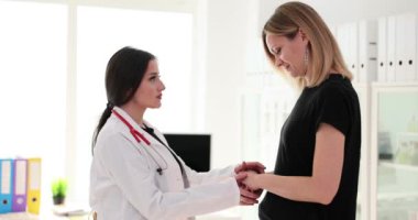 Kadın doktor, hamile bayana destek ve yardım sunan hastalara yardım sağlıyor. Randevuda hastalığın profesyonel tedavi yaklaşımları