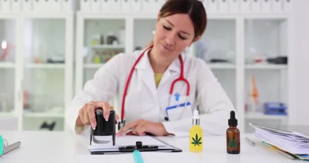 女性の薬理学者スタンプは 大麻ベースの製品を販売することを許可します 女性の医者はマリファナに注入された鎮静剤のための病気の顧客のための処方箋を書きます — ストック動画