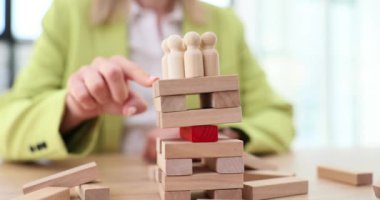 Kadın, kulenin dengesini korumak için tahta Jenga bloklarını dürtüyor. İş kadını bir sonraki hamlesini yavaş çekimde stratejik yaklaşım ile düşünüyor