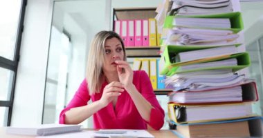 Kadın koca bir yığın yüzük klasörüne bakıyor. Yorgun suratlı bir ofis çalışanı masasında oturur ve ağır çekimde görevleri düşünür.