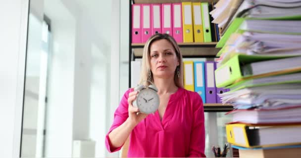 Yorgun Sarışın Kadın Klasörlerin Başında Oturup Çalar Saati Işaret Ediyor — Stok video