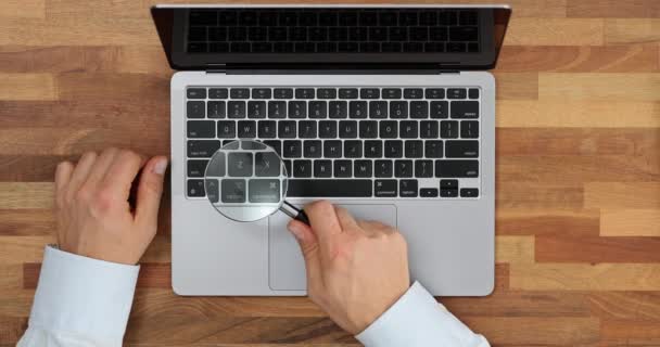 Mann Betrachtet Laptop Tastatur Durch Vergrößerungsglas Auf Holztisch Der Firma — Stockvideo
