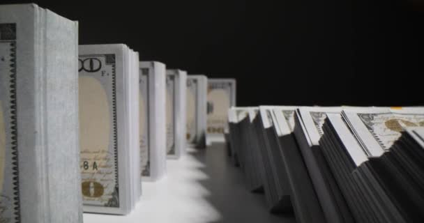ドル紙幣パックはスタジオの机にドミノ効果を発揮する 黒い背景に対して積み重ねられた現金 経済的な成功と豊かさ — ストック動画