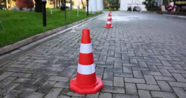 Şehir parkındaki kaldırımda renkli trafik konileri. Kasaba bölgesindeki yol çalışması için güvenlik ekipmanları. Araçları uzak tutan nesneler