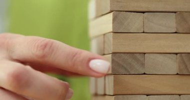 Eğlendirici Jenga oyununda kumarbaz neşeli arkadaşlara oyun başlatmak için uzun kuleden işlenmiş bir tahta parçası alır. Evde eğlence.