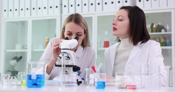Kafası Karışmış Kadın Laboratuvar Asistanları Mikroskopta Yerindeki Garip Örneklere Bakarlar — Stok video