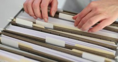 Kadın çalışan, şirket arşivindeki kutulardaki belgeleri düzenliyor. İş yerindeki verilerle yavaş çekimde çalışmak