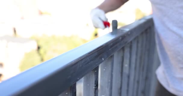 男建筑工人用专业的滚轮油漆公寓阳台金属围栏 年轻人在栅栏框架慢动作上用工具涂彩色颜料 — 图库视频影像