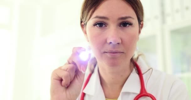 責任ある顔を持つ集中した医師は 助けを求める患者に小さな懐中電灯を輝かせます 健康遅い動きの状態をチェックするクライアントの検査 — ストック動画
