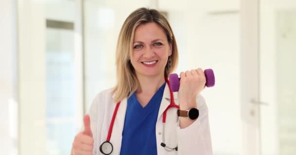 미소를 금발의 의사는 덤벨을 건강을 향상시키기 활발한 라이프 스타일에 엄지손가락 — 비디오
