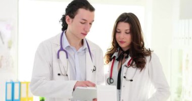 Doktorlar doğru teşhisler için hasta kayıtlarını tartışırlar. Doktorlar muayene odasında duruyor ve devam eden tedavilerin belgelerini inceliyorlar.