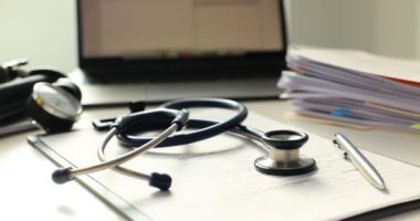 Stetoskop ve kağıtlar doktor masasının üzerinde düzgünce duruyor. Hasta muayenesinin yavaşlaması için masada tıbbi araçlar düzenlendi