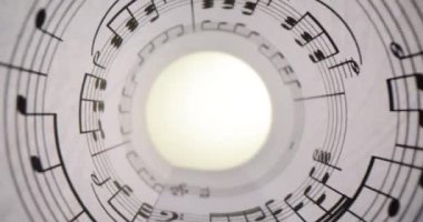 Yuvarlak kağıda sarılmış beyaz kağıtlar düzgün basılmış müzik notaları sergiliyor. Siyah mürekkeple basılmış müzik sembolleri müzikal kompozisyonun melodisini gösterir
