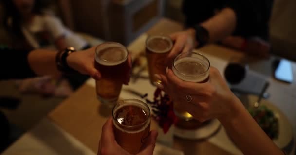亲密的朋友们在欢乐的半暗的气氛中 用啤酒轻敲透明的玻璃杯 欢欢喜喜的朋友聚在一起庆祝特别活动慢动作 — 图库视频影像