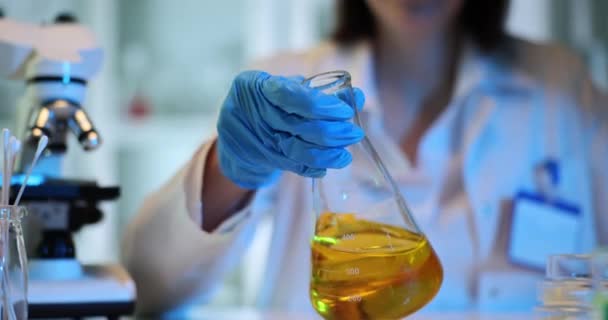 Wetenschapper Mengt Gele Olieachtige Vloeistof Laboratoriumbekerglas Efficiënte Laboratoriummedewerker Onderzoekt Vloeistof — Stockvideo