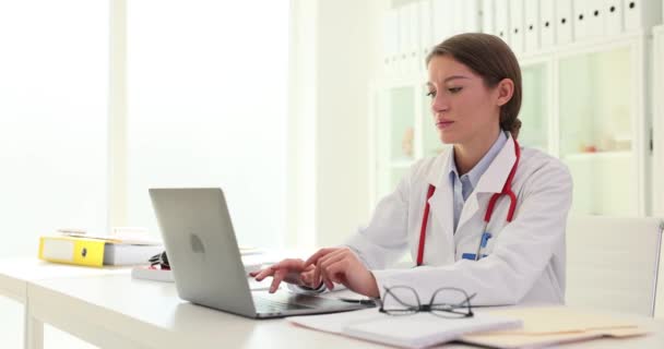 女性医師は電子システムに重要な情報を入力します 医師はラップトップを使用して 患者の相談の概要を遅い動きにタイプする — ストック動画
