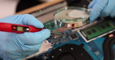 Eldiven lehimleyen kişi bilgisayardaki teknolojiyi geliştirmek için lehimleme demiriyle detaylı bilgi verir. Eller cihazdaki ekipman ve mikroçipi tamir eder