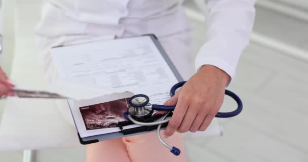 Γιατρός Εξετάζει Εικόνες Υπερήχων Και Γράφει Αναφορές Αρχεία Ασθενών Προσέγγιση — Αρχείο Βίντεο