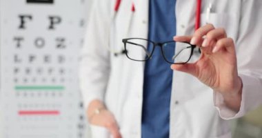 Oftalmolog hastane ofisinde hasta için uygun gözlük gösteriyor. Görme düzeltmesi için profesyonel seçenekler yavaş çekimde