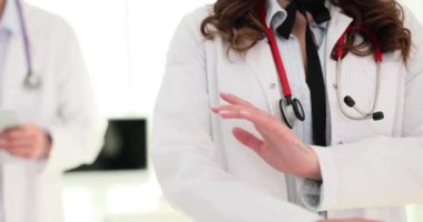 Kadın doktor, erkek hekime karşı kollarını kavuşturuyor. Sıhhiye, tıp mesleği için gerekli işbirliği ruhunu ve takım çalışmasını yansıtıyor