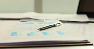 Finansal raporla ilgili belgeler ve kağıtlarla dolu bir masa. Detaylı analiz sağlamak için özenle hazırlanmış hayati bir bilgiyi görüntüle