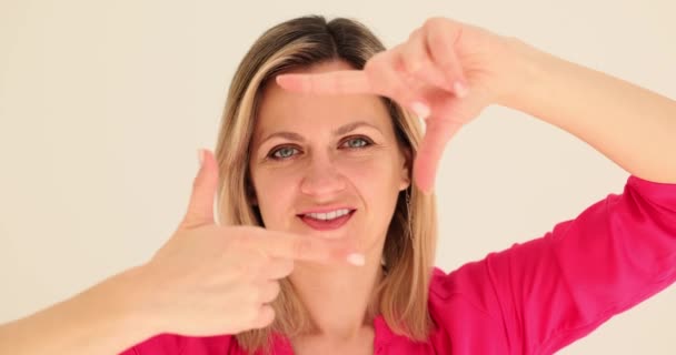 Modelo Mujer Sonriente Imita Enfoque Cámara Con Los Dedos Enmarcado — Vídeos de Stock